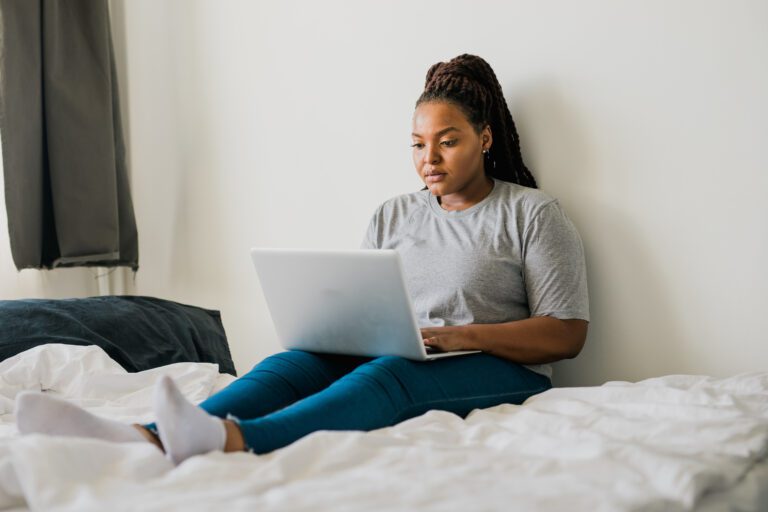 African american young woman using laptop on bed