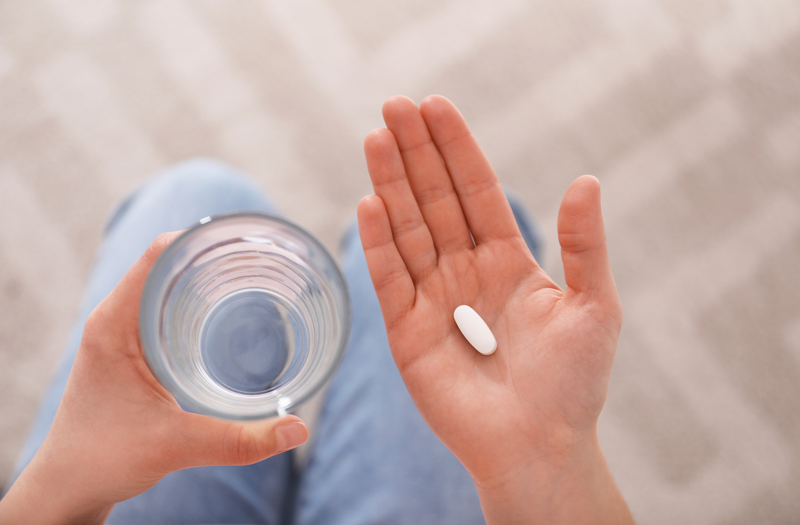 Young woman with abortion pill and glass of water, top view