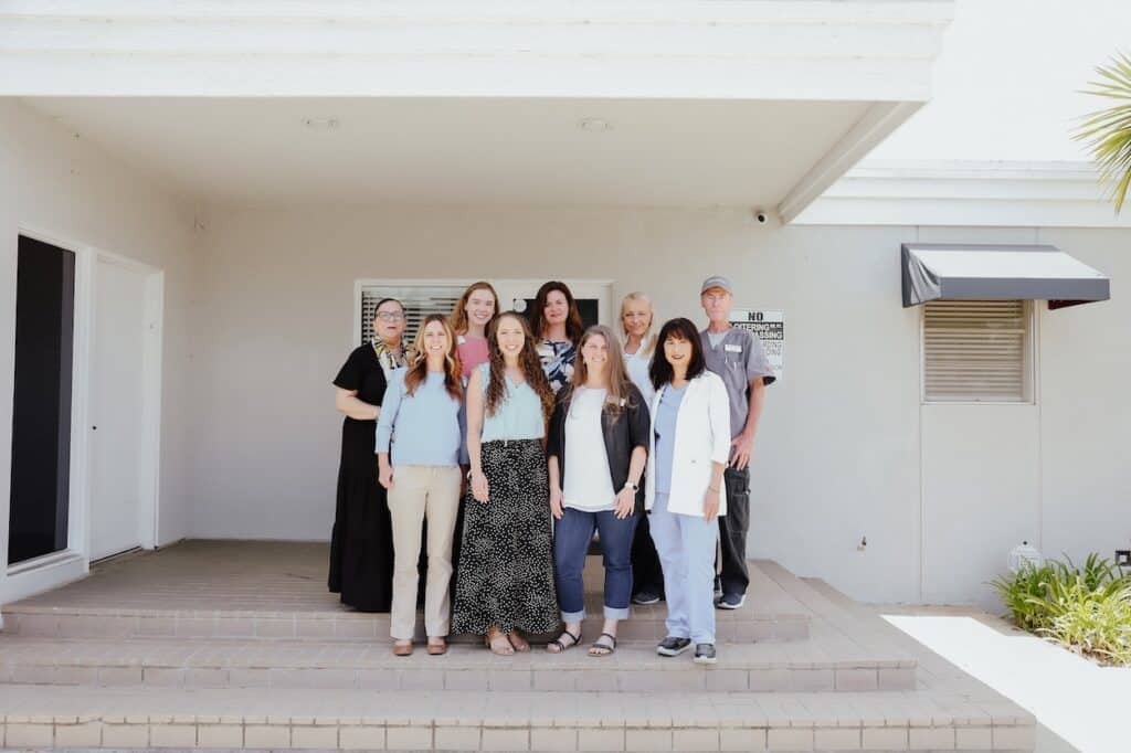 Group photo of Alternatives staff standing together outside the treatment center entrance.