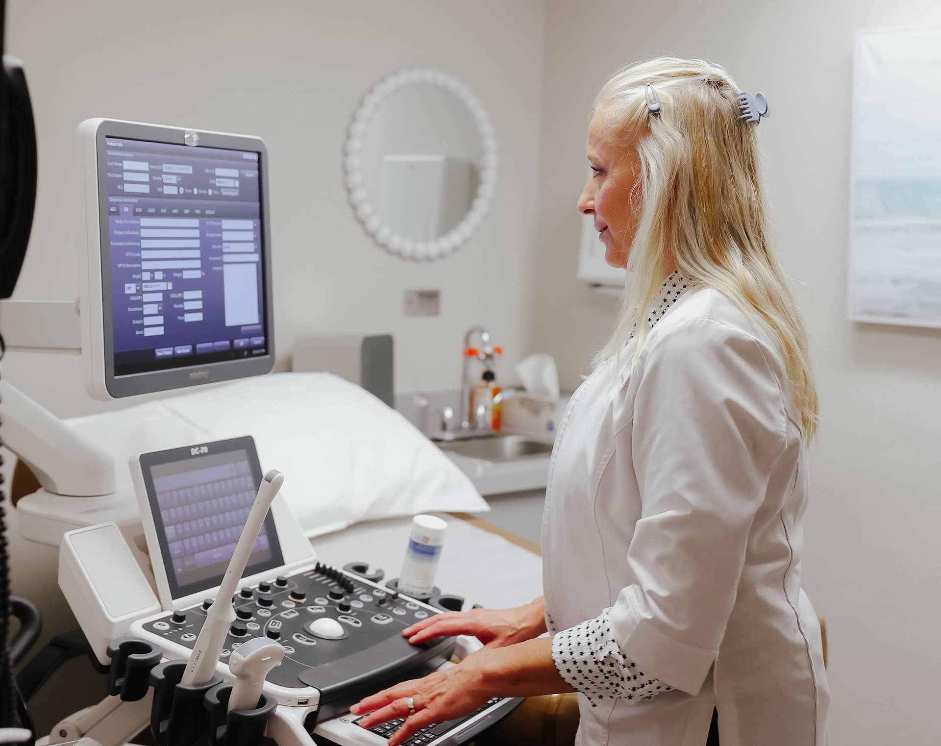 Healthcare professional operating an ultrasound machine in a medical exam room before a patient appointment.